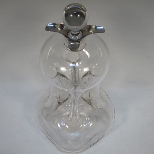 A handsome Antique Victorian Sterling Silver and cut-crystal glug-glug decanter, having a plain and clear body with pinched and fluted central waists, a plain round neck with four pouring spouts, and original hand-cut stopper. Made by William Hutton and Sons of Birmingham in 1901. The dimensions of this fine hand-made antique silver and crystal glug glug decanter are height 27.5 cms (10.75 inches), and width at base 13 cms (5 inches).