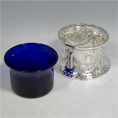 An Antique Edwardian Sterling silver miniature dish ring, having a hand-pierced and chased body with neoclassical style decoration, and a blue-glass liner. Made by Williams of Birmingham in 1910. The dimensions of this fine hand-made miniature silver dish ring are height 8 cms (2.3 inches), diameter at base 10 cms (4 inches), and it weighs approx. 85g (2.7 troy ounces).