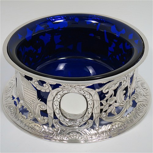 An Antique Victorian Sterling Silver large table dish ring in an Irish style, having a hand-pierced and chased body decorated with pastoral scenes, figures, animals, a vacant oval cartouche, and a blue-glass liner. Made by D. and J. Welby of London in 1894. The dimensions of this fine hand-made antique silver dish ring are height 7.5 cms (3 inches), diameter at base 19 cms (7.5 inches), and it weighs approx. 351g (11.3 troy ounces).    