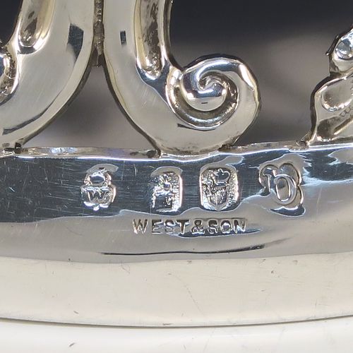 A very beautiful Irish Antique Sterling Silver large table dish ring, having a hand-pierced and chased body decorated with scrolls, flowers, and animals, a single vacant cartouche, and a blue-glass liner. This elegant silver potato or dish ring was made by West and Son of Dublin in 1917. The dimensions of this fine hand-made antique silver dish ring are height 10 cms (4 inches), diameter at base 18.5 cms (7.25 inches), and it weighs approx. 326g (10.5 troy ounces).