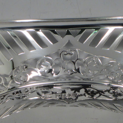 Antique Edwardian sterling silver bread roll table dish, having an oval body with hand-pierced geometrical and floral decoration, with an applied shaped reeded border, with two scroll side handles, and sitting on a flat base. Made by Charles Clement Pilling of London in 1902. The dimensions of this fine hand-made silver bread dish are length 32.5 cms (12.75 inches), width 18 cms (7 inches), height 6.5 cms (2.5 inches), and it weighs approx. 304g (9.8 troy ounces).