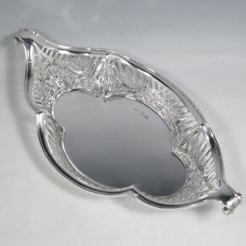 Antique Edwardian sterling silver bread roll table dish, having an oval body with hand-pierced geometrical and floral decoration, with an applied shaped reeded border, with two scroll side handles, and sitting on a flat base. Made by Charles Clement Pilling of London in 1902. The dimensions of this fine hand-made silver bread dish are length 32.5 cms (12.75 inches), width 18 cms (7 inches), height 6.5 cms (2.5 inches), and it weighs approx. 304g (9.8 troy ounces).