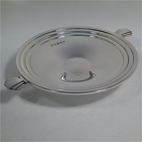 A very handsome and stylish Sterling Silver Art Deco dish, having a round body with hand-chased reeded decoration, together with two hand-cut stepped side handles, and sitting on a low pedestal foot. Made by the Barker Brothers of Birmingham in 1934. The dimensions of this fine hand-made Art Deco silver serving dish are diameter 21.5 cms (8.5 inches), height 4 cms (1.5 inches), and it weighs approx. 335g (10.8 troy ounces).