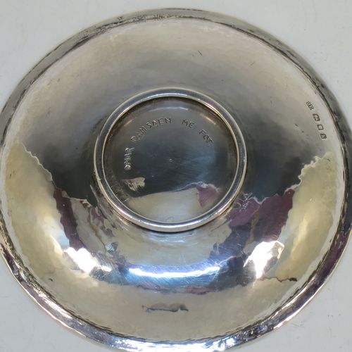 A very beautiful Sterling Silver Arts and Crafts table dish, having a round hand-hammered body, with an applied reed cog border, a central Tudor Rose style boss with an applied rope-twist border and dark red enamel underneath showing through the piercing, and all sitting on a collet foot. Made by Omar Ramsden of London in 1923. The dimensions of this fine hand-made Arts and Crafts silver dish are diameter 11 cms (4.3 inches), and it weighs approx. 93g (3 troy ounces).