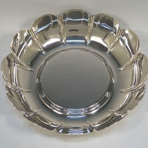 A very large, heavy, and handsome Sterling Silver strawberry dish, having a plain round body, with a raised flat ground, melon fluted sides with hand-chased lobed edges. This elegant silver dish was made by the Royal Irish Silver Co., of London in 1973. The dimensions of this fine hand-made table dish are diameter 33 cms (13 inches), height 8.5 cms (3.3 inches), and it weighs approx. 1,302g (42 troy ounces).