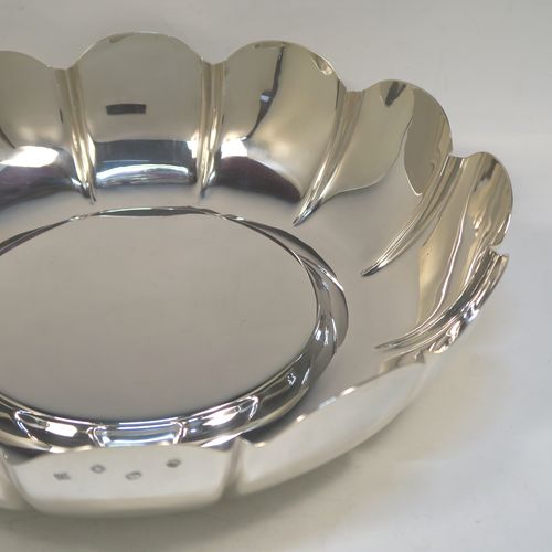 A very large, heavy, and handsome Sterling Silver strawberry dish, having a plain round body, with a raised flat ground, melon fluted sides with hand-chased lobed edges. This elegant silver dish was made by the Royal Irish Silver Co., of London in 1973. The dimensions of this fine hand-made table dish are diameter 33 cms (13 inches), height 8.5 cms (3.3 inches), and it weighs approx. 1,302g (42 troy ounces).