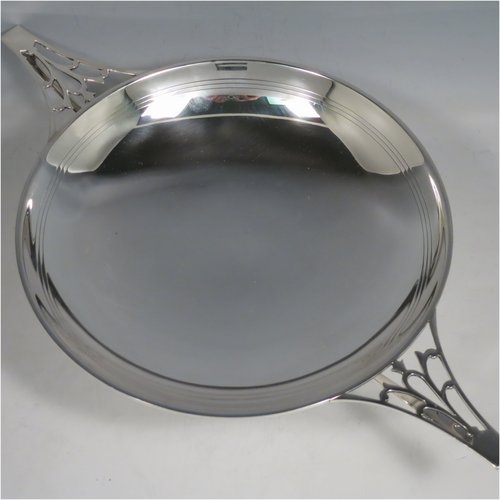 A Sterling Silver Art Deco very stylish serving dish, having a plain round body, with a band of hand-engraved reed-work, and two hand-pierced handles, all sitting on a pedestal foot. Made by William Naylor of Birmingham in 1935. The dimensions of this fine hand-made silver Art Deco dish are width across handles 36.5 cms (14.3 inches), height 7.5 cms (3 inches), and it weighs approx. 520g (16.8 troy ounces).