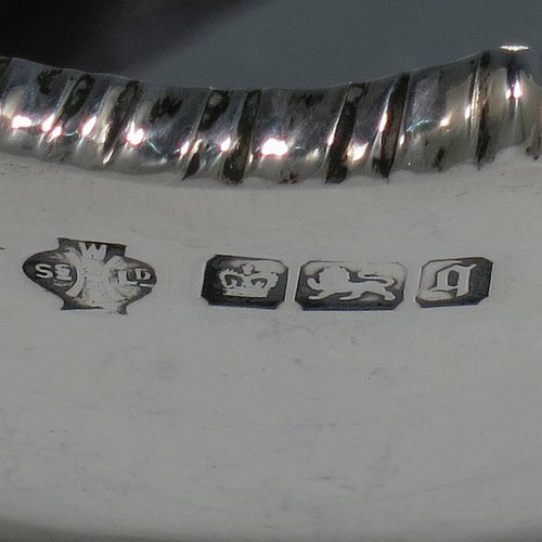 An Antique Edwardian Sterling Silver bread roll table dish, having an oval plain body with an applied wavey-edged rope-twist or gadroon border, and sitting on a flat base. Made by William Hutton & Sons of Sheffield in 1908. The dimensions of this fine hand-made antique silver bread dish are length 20 cms (8 inches), width 15 cms (6 inches), height 7 cms (2.75 inches), and it weighs approx. 285g (9.2 troy ounces).