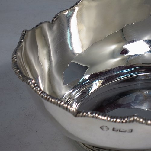 An Antique Edwardian Sterling Silver bread roll table dish, having an oval plain body with an applied wavey-edged rope-twist or gadroon border, and sitting on a flat base. Made by William Hutton & Sons of Sheffield in 1908. The dimensions of this fine hand-made antique silver bread dish are length 20 cms (8 inches), width 15 cms (6 inches), height 7 cms (2.75 inches), and it weighs approx. 285g (9.2 troy ounces).