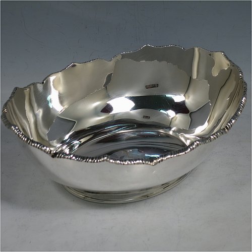 An Antique Edwardian Sterling Silver bread roll table dish, having an oval plain body with an applied wavey-edged rope-twist or gadroon border, and sitting on a flat base. Made by William Hutton & Sons of Sheffield in 1908. The dimensions of this fine hand-made antique silver bread dish are length 20 cms (8 inches), width 15 cms (6 inches), height 7 cms (2.75 inches), and it weighs approx. 285g (9.2 troy ounces).