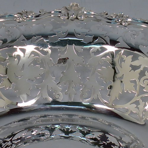 An Antique Edwardian Sterling Silver serving dish, having a round body, with an applied cast scroll and shell border, a hand-pierced body with floral decoration, and sitting on a plain flat collet foot. Made by Alexander Clark of Sheffield in 1906. The dimensions of this fine hand-made antique silver serving dish are 27 cms (10.5 inches) diameter, height 6 cms (2.3 inches), and it weighs approx. 460g (14.8 troy ounces).