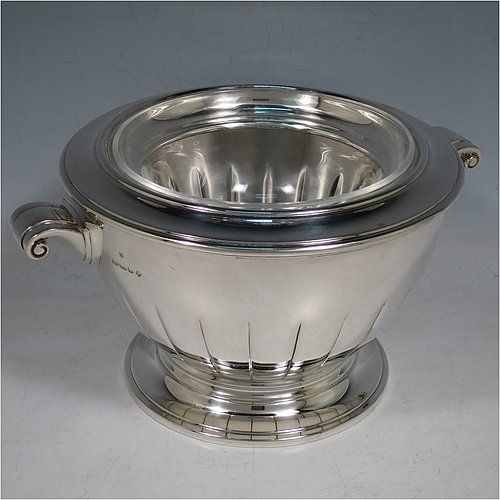 A Sterling Silver Caviar serving dish in an Art Deco style, having a round body with hand-chased straight half-fluting, with two cast scroll side-handles, a removable glass bowl that sits on a rim below which crushed ice can be added, and sitting on a matching pedestal foot. Made by Aspreys & Garrards of London in 2000. The dimensions of this fine hand-made silver caviar serving dish are 17 cms (6..75 inches) diameter, height 11.5 cms (4.5 inches), and it weighs approx. 840g (27 troy ounces).    