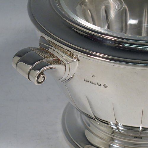 A Sterling Silver Caviar serving dish in an Art Deco style, having a round body with hand-chased straight half-fluting, with two cast scroll side-handles, a removable glass bowl that sits on a rim below which crushed ice can be added, and sitting on a matching pedestal foot. Made by Aspreys & Garrards of London in 2000. The dimensions of this fine hand-made silver caviar serving dish are 17 cms (6..75 inches) diameter, height 11.5 cms (4.5 inches), and it weighs approx. 840g (27 troy ounces).