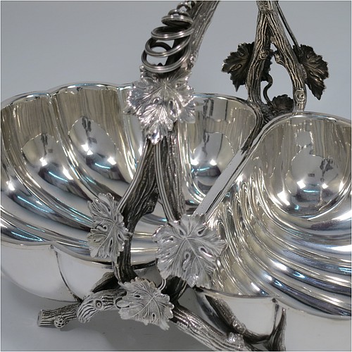 An Antique Victorian Silver Plated very unusual double shell bread roll or biscuit dish, having two connected side dishes with hand-chased shell style decoration, with a central cast vine-leaf and tendril handle, and sitting on four cast branch-like feet. Made by Mappin and Webb in their Princes Plate in ca. 1880. The dimensions of this fine hand-made antique silver-plated biscuit or bread roll dish are length 30 cms (11.75 inches), width 20 cms (8 inches), and height 17 cms (6.75 inches).