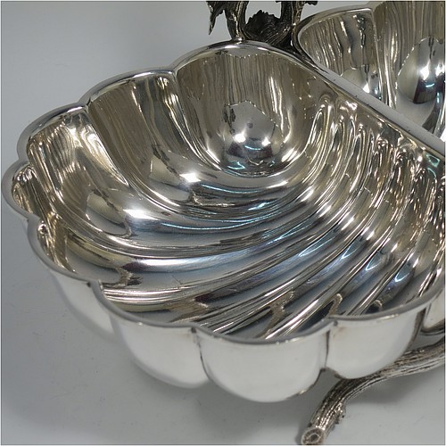 An Antique Victorian Silver Plated very unusual double shell bread roll or biscuit dish, having two connected side dishes with hand-chased shell style decoration, with a central cast vine-leaf and tendril handle, and sitting on four cast branch-like feet. Made by Mappin and Webb in their Princes Plate in ca. 1880. The dimensions of this fine hand-made antique silver-plated biscuit or bread roll dish are length 30 cms (11.75 inches), width 20 cms (8 inches), and height 17 cms (6.75 inches).