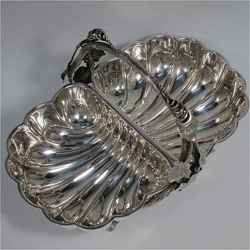 An Antique Victorian Silver Plated very unusual double shell bread roll or biscuit dish, having two connected side dishes with hand-chased shell style decoration, with a central cast vine-leaf and tendril handle, and sitting on four cast branch-like feet. Made by Mappin and Webb in their Princes Plate in ca. 1880. The dimensions of this fine hand-made antique silver-plated biscuit or bread roll dish are length 30 cms (11.75 inches), width 20 cms (8 inches), and height 17 cms (6.75 inches).