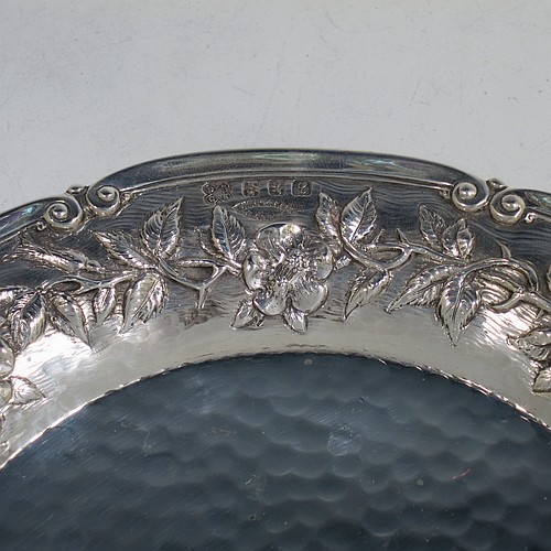 A very pretty Scottish Sterling Silver Arts and Crafts style table dish, having a round hand-hammered body, with an applied scroll border and hand-chased floral wild rose and thorn-leaf decoration. Made by Edward and Sons of Glasgow in 1922. The dimensions of this fine hand-made Arts and Crafts silver dish are diameter 18 cms (7 inches), and it weighs approx. 203g (6.5 troy ounces).