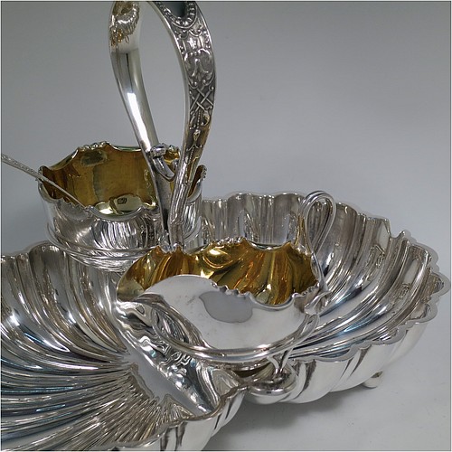 An Antique Victorian Silver-Plated strawberry dish, having two melon-fluted fixed shell dishes, a removable sugar bowl and cream jug both with gold-gilt interiors, an original sugar sifting ladle, and all sitting in a frame with loop handle and four ball feet. Made by James Dixon and Sons of Sheffield in ca. 1880. The dimensions of this fine hand-made antique silver-plated double strawberry dish are length 32 cms (12.5 inches), width 20 cms (8 inches), and height 22 cms (8.75 inches).