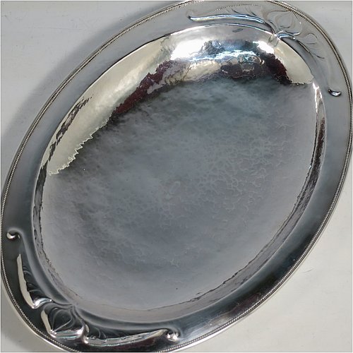A Sterling Silver Arts and Crafts style dish, having an oval body with hand-hammered decoration, an applied rope-twist border, with hand-chased floral and scroll work at either ends, and all sitting on a collet foot. Made by Henry Charles Hall (from the Swansea School of Crafts) of Sheffield in 1932. The dimensions of this fine hand-made silver table dish are length 31 cms (12.25 inches), width 21 cms (8.25 inches), height 4 cms (1.5 inches), and it weighs approx. 464g (15 troy ounces).
