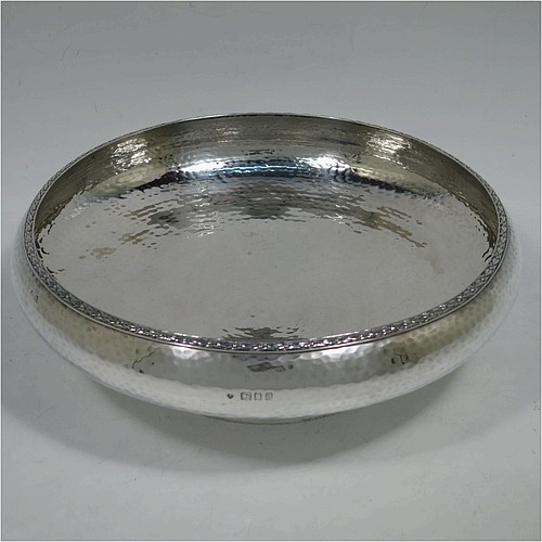A very pretty Sterling Silver Arts and Crafts style table dish, having a round hand-hammered body, with an applied floral border, and sitting on a collet foot. Made by the Fenton Brothers Ltd., of London in 1922. The dimensions of this fine hand-made Arts and Crafts silver dish are diameter 22 cms (8.75 inches), height 7 cms (2.75 inches), and it weighs approx. 370g (12 troy ounces).    