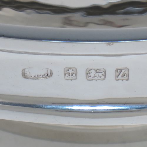 A very handsome and stylish Antique Sterling Silver Art and Crafts style dish, having a round body with hand-hammered decoration, a top border with applied round swirl motifs, and sitting on a low pedestal foot. Made by A. E. Jones of Birmingham in 1924. The dimensions of this fine hand-made Art and Crafts antique silver serving dish are diameter 20 cms (8 inches), height 7 cms (2.75 inches), and it weighs approx. 334g (10.8 troy ounces).