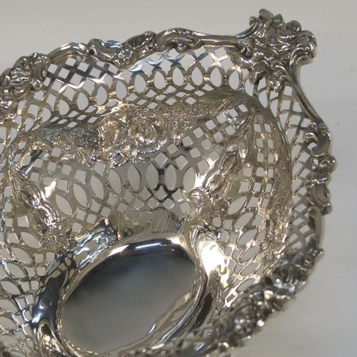 A very pretty pair of Antique Victorian Sterling Silver dishes, having oval bodies with neoclassical style decoration, hand-pierced with swags and bows and applied cast foliate borders, all sitting on matching oval pedestal feet. These beautiful antique silver dishes were made by Charles Stuart Harris of London in 1900. The dimensions of these fine hand-made silver table dishes are length 19 cms (7.5 inches), width 14 cms (5.5 inches), height 11 cms (4.3 inches), and they weigh a total of approx. 627g (20 troy ounces).
