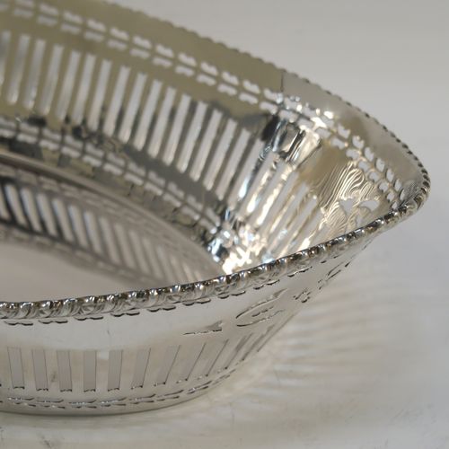 A very pretty Antique Sterling Silver bread roll table dish, having an oval body with hand-pierced geometrical and floral style decoration, an applied gadroon top border, and sitting on a flat base. This beautiful antique silver bread roll dish was made by the Barker Brothers of Chester in 1911. The dimensions of this fine hand-made silver bread dish are length 30 cms (11.75 inches), width 17.5 cms (7 inches), height 7.5 cms (3 inches), and it weighs approx. 389g (12.5 troy ounces).