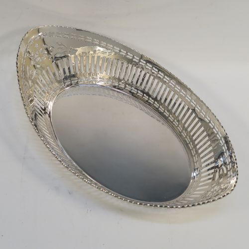 A very pretty Antique Sterling Silver bread roll table dish, having an oval body with hand-pierced geometrical and floral style decoration, an applied gadroon top border, and sitting on a flat base. This beautiful antique silver bread roll dish was made by the Barker Brothers of Chester in 1911. The dimensions of this fine hand-made silver bread dish are length 30 cms (11.75 inches), width 17.5 cms (7 inches), height 7.5 cms (3 inches), and it weighs approx. 389g (12.5 troy ounces).
