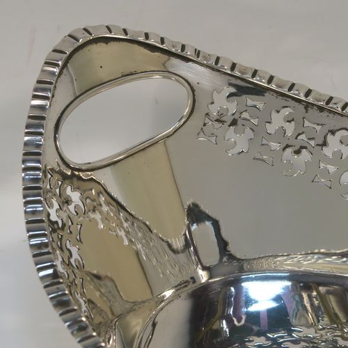 A very elegant Antique Victorian sterling silver bread roll table dish, having an oval body with hand-pierced floral style decoration, an applied gadroon top border, with two cut-out oval side handles, and sitting on a flat base. This handsome antique silver bread roll dish was made by Gibson and Langland of London in 1899. The dimensions of this fine hand-made silver bread dish are length 27.5 cms (10.75 inches), width 17 cms (6.75 inches), height 9 cms (3.5 inches), and it weighs approx. 538g (17.4 troy ounces).