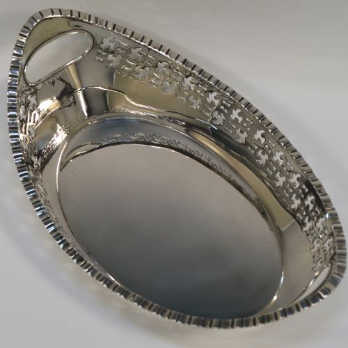A very elegant Antique Victorian sterling silver bread roll table dish, having an oval body with hand-pierced floral style decoration, an applied gadroon top border, with two cut-out oval side handles, and sitting on a flat base. This handsome antique silver bread roll dish was made by Gibson and Langland of London in 1899. The dimensions of this fine hand-made silver bread dish are length 27.5 cms (10.75 inches), width 17 cms (6.75 inches), height 9 cms (3.5 inches), and it weighs approx. 538g (17.4 troy ounces).