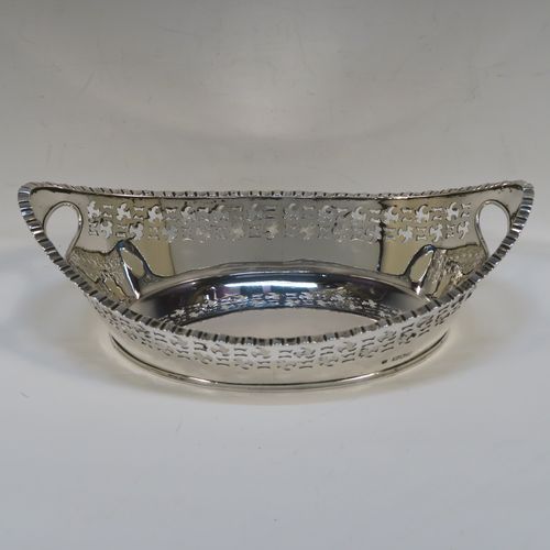 A very elegant Antique Victorian sterling silver bread roll table dish, having an oval body with hand-pierced floral style decoration, an applied gadroon top border, with two cut-out oval side handles, and sitting on a flat base. This handsome antique silver bread roll dish was made by Gibson and Langland of London in 1899. The dimensions of this fine hand-made silver bread dish are length 27.5 cms (10.75 inches), width 17 cms (6.75 inches), height 9 cms (3.5 inches), and it weighs approx. 538g (17.4 troy ounces).
