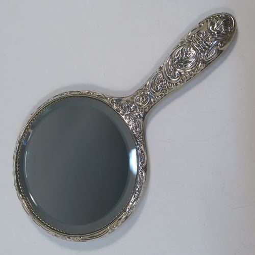 A very pretty Sterling Silver four-piece dressing table, consisting of a hand-mirror with a bevelled mirror, a hair brush, a clothes brush, and a hand comb, all hand-chased with floral and scroll decoration, with nylon bristles, and in their original cream satin-lined and blue presentation box. This beautiful silver dressing table set was made in Birmingham in 2002. The dimensions of this fine hand-made sterling silver dressing table service are length of hand mirror 24 cms (9.5 inches), length of hair brush 23 cms (9 inches), and length of clothes brush 15 cms (6 inches).