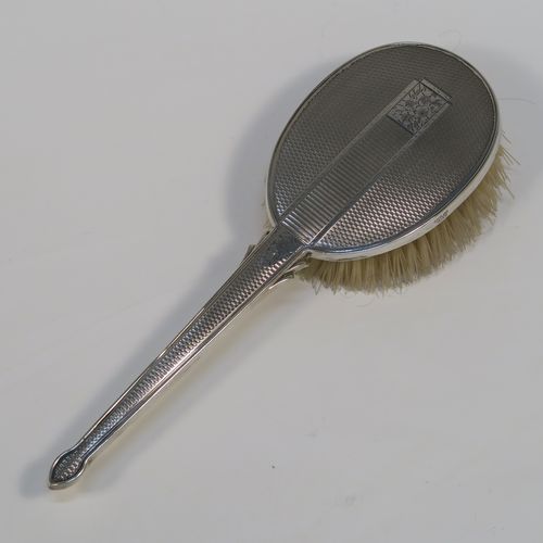 A beautiful Sterling Silver Art Deco style dressing table set with four pieces, consisting of a hand-mirror with original bevelled mirror, a clothes brush, a hair brush, all with original bristles, and an original comb, all with engine-turned decoration and central floral style cartouches. This very pretty silver dressing table set was made by Broadway and Co., of Birmingham in 1957. The dimensions of this fine hand-made sterling silver dressing table service are length of mirror 26 cms (10.25 inches), length of hair brush 24 cms (9.5 inches), and length of clothes brush 14.5 cms (5.57 inches).