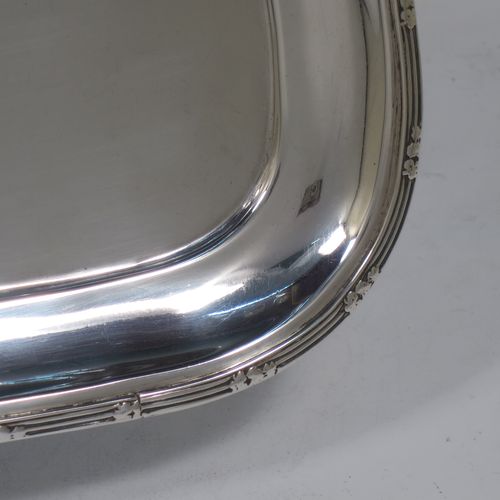 A pretty Antique Edwardian Sterling Silver dressing table tray, having a rectangular body with rounded corners, a plain ground, an applied laurel-leaf and reeded border, and all sitting on a flat base. Made by Harrison Brothers and Howson of Sheffield in 1910. The dimensions of this fine hand-made ique antsilver dressing table tray are length 30 cms (12 inches), width 22 cms (8.75 inches), and it weighs approx. 512g (16.5 troy ounces).    