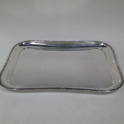 A pretty Antique Edwardian Sterling Silver dressing table tray, having a rectangular body with rounded corners, a plain ground, an applied laurel-leaf and reeded border, and all sitting on a flat base. Made by Harrison Brothers and Howson of Sheffield in 1910. The dimensions of this fine hand-made ique antsilver dressing table tray are length 30 cms (12 inches), width 22 cms (8.75 inches), and it weighs approx. 512g (16.5 troy ounces).    
