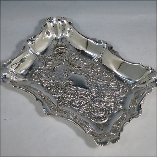 An Antique Victorian Sterling Silver Art Nouveau dressing table pin tray, having a shaped rectangular body with a raised border and hand-chased floral and scroll decoration, a central vacant cartouche, and all sitting on a flat base. Made by the Fenton Brothers of Sheffield in 1896. The dimensions of this fine hand-made antique silver pin tray are length 25 cms (10 inches), width 19 cms (7.5 inches), and it weighs approx. 294g (9.5 troy ounces).    