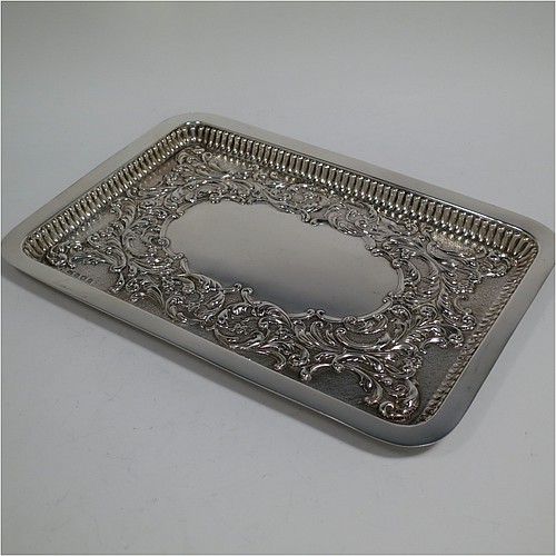 An Antique Edwardian Sterling Silver dressing table pin tray, having a rectangular body with a raised fluted border, hand-chased floral and scroll decoration on a hand-hammered ground, with a central vacant cartouche, and all sitting on a flat base. Made by William Aitken of Birmingham in 1909. The dimensions of this fine hand-made antique silver pin or dressing table tray are length 27 cms (10.5 inches), width 19 cms (7.5 inches), and it weighs approx. 216g (7 troy ounces).