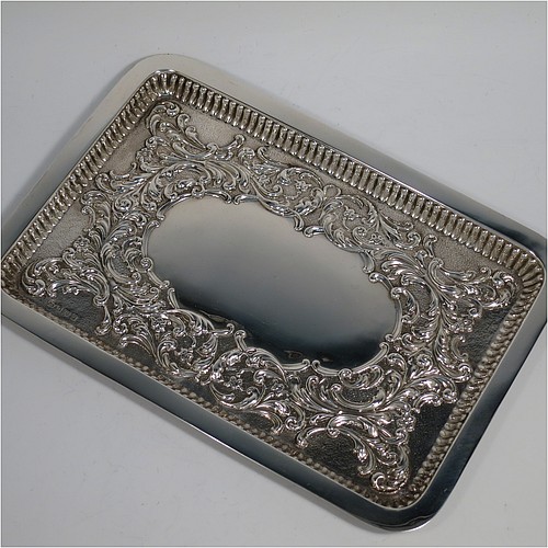 An Antique Edwardian Sterling Silver dressing table pin tray, having a rectangular body with a raised fluted border, hand-chased floral and scroll decoration on a hand-hammered ground, with a central vacant cartouche, and all sitting on a flat base. Made by William Aitken of Birmingham in 1909. The dimensions of this fine hand-made antique silver pin or dressing table tray are length 27 cms (10.5 inches), width 19 cms (7.5 inches), and it weighs approx. 216g (7 troy ounces).