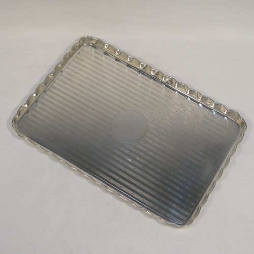 A very pretty Antique Sterling Silver dressing table or pen tray, having a rectangular body with a raised melon fluted border and rounded corners, an engine-turned ground with a central vacant round cartouche, and all sitting on a flat base. This beautiful dressing table or pen tray was made by James Deakin and Son of Birmingham in 1912. The dimensions of this fine hand-made antique silver pen or dressing table tray are length 27 cms (10.5 inches), width 18.5 cms (7.25 inches), and it weighs approx. 403g (13 troy ounces).