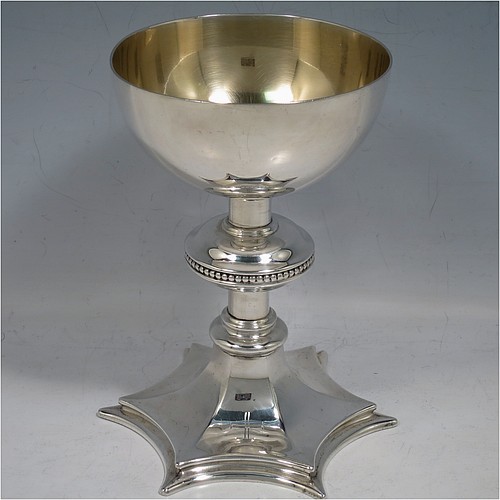 A Sterling Silver altar chalice and paten, having a plain round tapering cup with gold-gilt interior, a round column with a middle baluster and bead border, and a spreading hexagonal pedestal foot, together with a plain round paten with hand-engraved cross. The chalice made by Frederick Osborne of London in 1931, and the paten by Jones and Willis of London in 1908. The dimensions of this fine hand-made silver chalice & paten are height 15 cms (6 inches), diameter of cup 10 cms (4 inches), diameter of paten 13.5 cms (5.3 inches), and it weighs a total of 455g (14.7 troy ounces).
