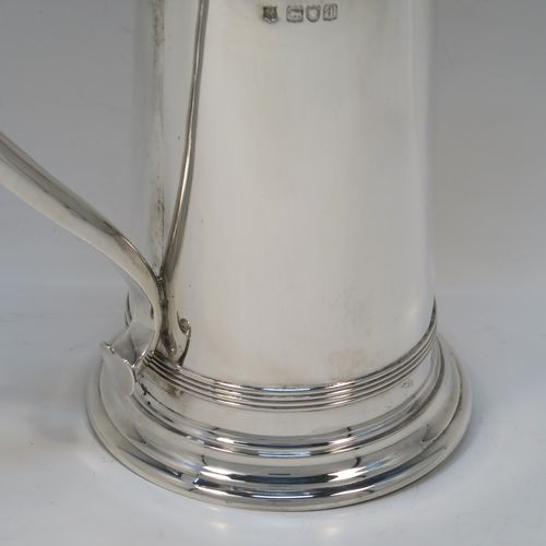 A handsome Antique Victorian Sterling Silver ecclesiastical wine flagon ewer, having a round straight-sided body and applied reeded bands, a side scroll handle, together with a hinged domed lid and cast round finial, a covered sparrow-beak spout, and sitting on a spreading collet foot. This elegant silver church consecrated wine flagon was made by William Gibson and John Langland of London in 1899. The dimensions of this fine hand-made antique silver flagon or ewer are height 24 cms (9.5 inches), diameter at base 11 cms (4.25 inches), and it weighs approx. 677g (21.8 troy ounces).