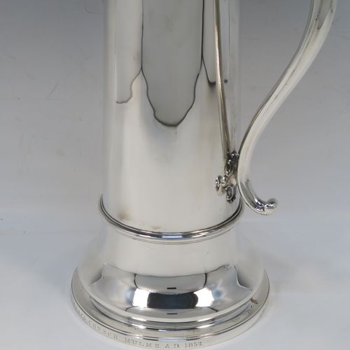 A handsome and large Antique Victorian Sterling Silver ecclesiastical wine flagon ewer, having a round straight-sided body with tapering sides and applied reeded bands, a side scroll handle, together with a hinged domed lid and cast fluted finial, a sparrow-beak spout, and sitting on a spreading collet foot. This elegant silver church consecrated wine flagon was made by the Barnard Brothers of London in 1850. The dimensions of this fine hand-made antique silver flagon or ewer are height 34.5 cms (13.5 inches), diameter at base 14.5 cms (5.75 inches), and it weighs approx. 980g (31.6 troy ounces).