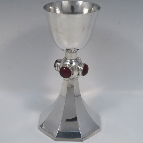 A very stylish Art Deco Sterling Silver altar chalice having a round hand-hammered or planished tapering cup, a panelled stem with four central applied red garnet coloured cabochon jewels, and all sitting on a spreading octagonal panelled base. This beautiful silver altar chalice was made made by J L A of London in 1936. The dimensions of this fine hand-made Art Deco silver chalice are height 21 cms (8.25 inches), diameter at lip of cup 8.5 cms (3.3 inches), spread across base 11 cms (4.3 inches), and it weighs approx. 365g (11.7 troy ounces).   