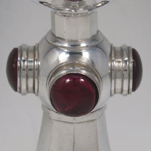 A very stylish Art Deco Sterling Silver altar chalice having a round hand-hammered or planished tapering cup, a panelled stem with four central applied red garnet coloured cabochon jewels, and all sitting on a spreading octagonal panelled base. This beautiful silver altar chalice was made made by J L A of London in 1936. The dimensions of this fine hand-made Art Deco silver chalice are height 21 cms (8.25 inches), diameter at lip of cup 8.5 cms (3.3 inches), spread across base 11 cms (4.3 inches), and it weighs approx. 365g (11.7 troy ounces).