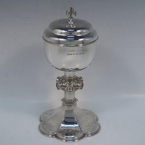 A beautiful Antique Victorian Sterling Silver Ciborium, having a plain round bellied body and a gold-gilt interior, sitting on a pedestal foot with a central applied jewel-like and floral baluster and a hand-engraved hexafoil foot with an applied bead-edged border, and a domed lift-off lid with cruciform finial and hand-engraved decoration. This wonderful silver ciborium was made by John Hardman and Co., of Birmingham in 1874. The dimensions of this fine hand-made antique silver ciborium are height 21.5 cms (8.5 inches), diameter of cup 9 cms (3.5 inches), and it weighs approx. 393g (12.6 troy ounces).   