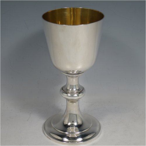 An Antique Victorian Sterling Silver communion service composed of a flagon and two goblets. The flagon in an early 17th century style having a straight-sided body, a scroll handle, a hinged & domed lid with urn-shaped finial, a matching scrolled spout and sitting on a collet foot. Together with a pair of plain round baluster goblets with gold-gilt interiors. All made by Robert Garrard of London in 1862/63. The dimensions of this fine hand-made communion set are height of flagon 29 cms (11.5 inches), length across handle & spout 23 cms (9 inches), height of goblets 18 cms (7 inches), and with a total weight of approx. 1,643g (53 troy ounces).