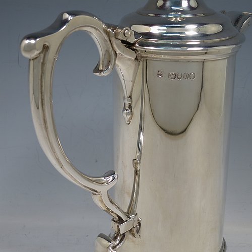 An Antique Victorian Sterling Silver communion flagon for wine, in an early 17th century style having a straight-sided body, a scroll handle, a hinged & domed lid with urn-shaped finial, a matching scrolled spout and sitting on a collet foot. Made by Robert Garrard of London in 1863. The dimensions of this fine hand-made communion flagon are height 29 cms (11.5 inches), length across handle & spout 23 cms (9 inches),and it weighs approx. 1,092g (35 troy ounces).