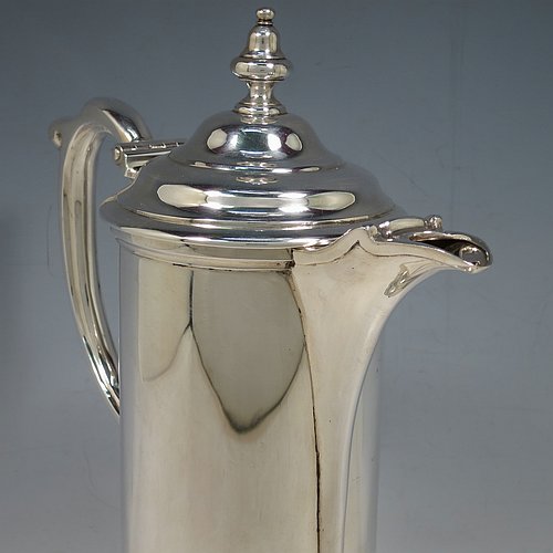 An Antique Victorian Sterling Silver communion flagon for wine, in an early 17th century style having a straight-sided body, a scroll handle, a hinged & domed lid with urn-shaped finial, a matching scrolled spout and sitting on a collet foot. Made by Robert Garrard of London in 1863. The dimensions of this fine hand-made communion flagon are height 29 cms (11.5 inches), length across handle & spout 23 cms (9 inches),and it weighs approx. 1,092g (35 troy ounces).