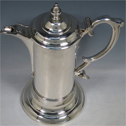 An Antique Victorian Sterling Silver communion flagon for wine, in an early 17th century style having a straight-sided body, a scroll handle, a hinged & domed lid with urn-shaped finial, a matching scrolled spout and sitting on a collet foot. Made by Robert Garrard of London in 1863. The dimensions of this fine hand-made communion flagon are height 29 cms (11.5 inches), length across handle & spout 23 cms (9 inches),and it weighs approx. 1,092g (35 troy ounces).
