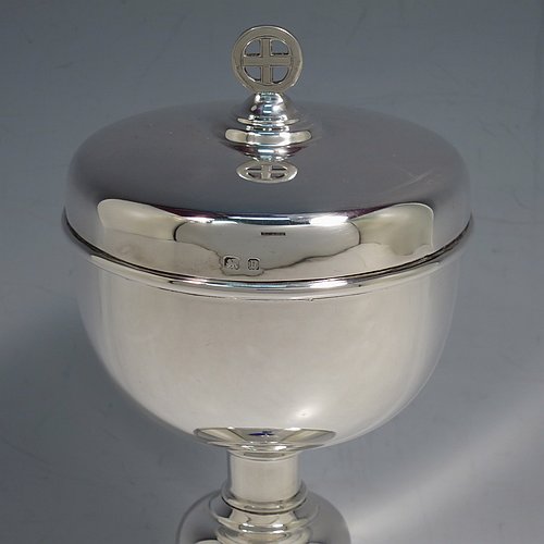 A Sterling Silver Ciborium, having a plain round body, sitting on a matching pedestal foot with an applied oval dark blue cabochon stone, with reeded borders, and a lift-off lid with cruciform finial. Made by Frederick Osborne & Co., of Birmingham in 1930. The dimensions of this fine hand-made silver ciborium are height 20 cms (8 inches), diameter of cup 9.5 cms (3.75 inches), and it weighs a total of approx. 385g (12.5 troy ounces).